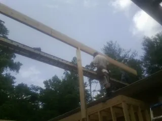 Carpenter setting a ridge beam over a new addition frame — Ice Dam Removal by Roofing Brothers in Loganville