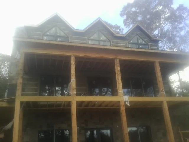 Dormers and porch framing on a large log home under construction — Roof Coating work by our crew in Loganville